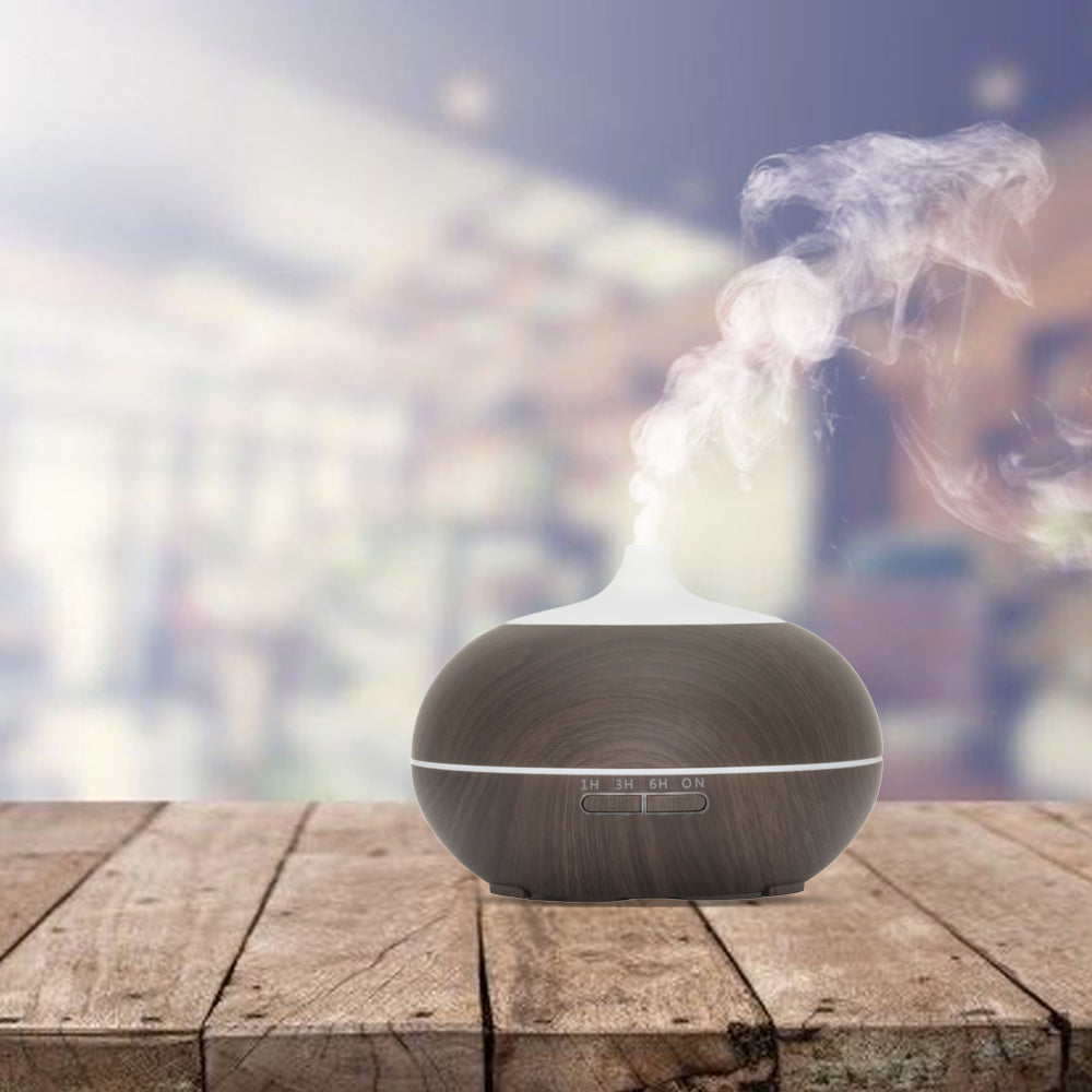 Compacte aroma diffuser in donker houtlook met een witte kap, inclusief afstandsbediening. Voorzien van instelbare timer (1u, 3u, 6u) en LED-verlichting.