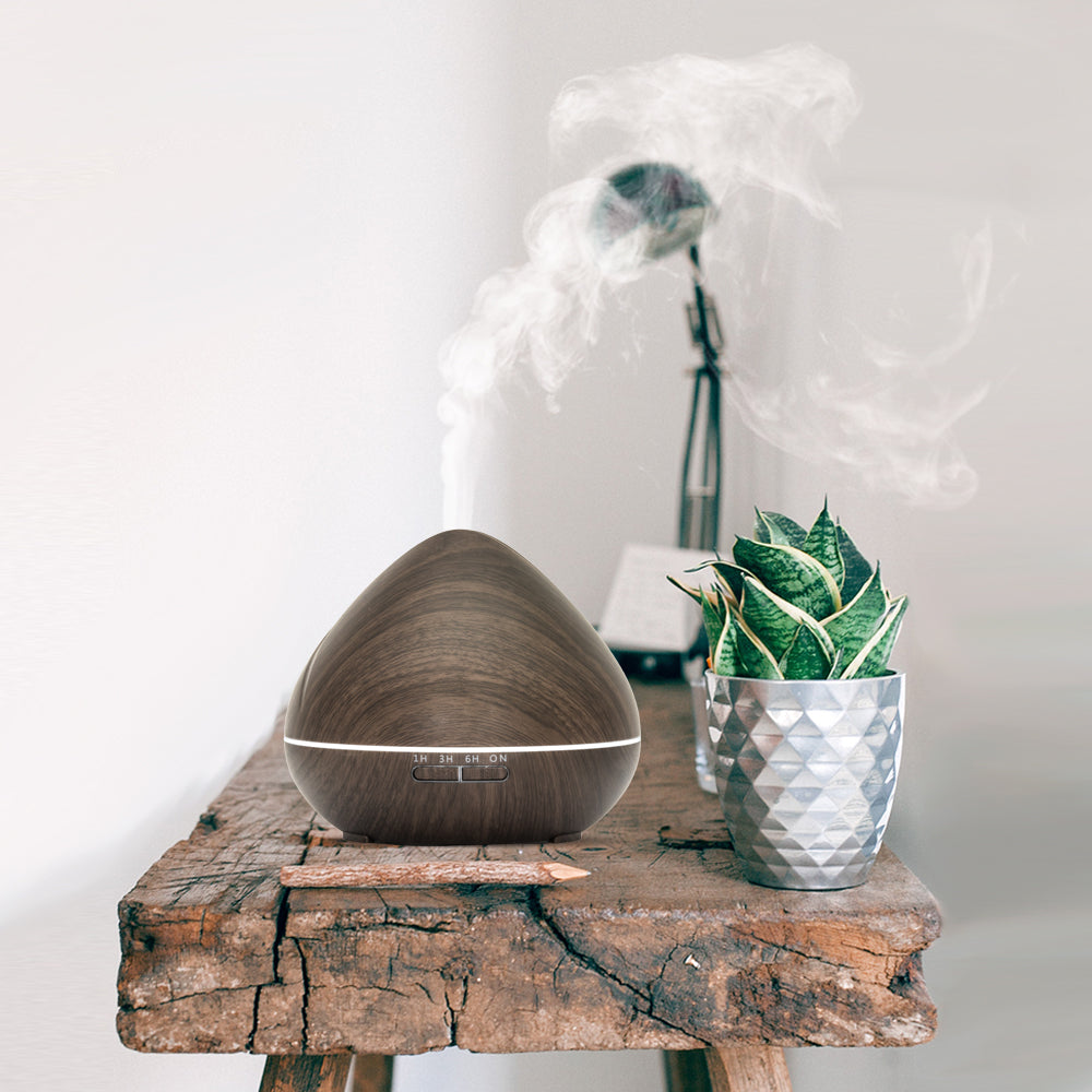 Houten aroma diffuser in druppelvorm met LED-licht, afstandsbediening, timeropties (1u, 3u, 6u, continu) en instelbare lichtinstellingen.