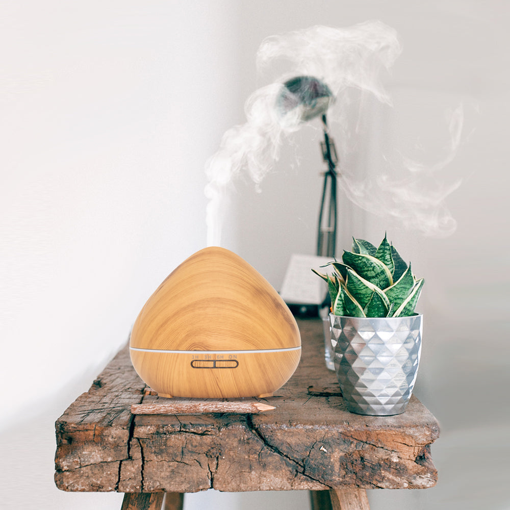 Lichte houten aroma diffuser in druppelvorm met LED-lichtstrip en afstandsbediening. Inclusief timeropties (1u, 3u, 6u, continu) en lichtinstellingen.