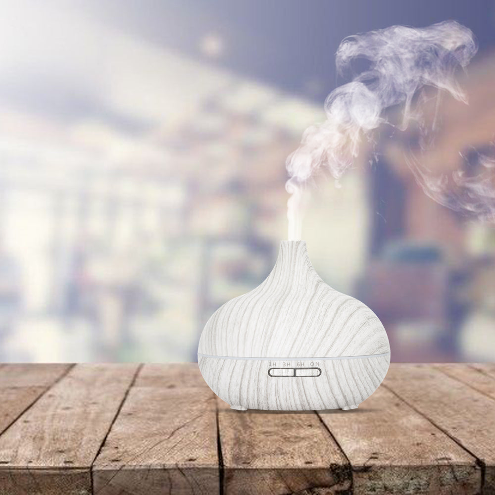 Stijlvolle aroma diffuser in witte houtlook met een sierlijke ronde vorm, inclusief afstandsbediening. Met instelbare timer (1u, 3u, 6u) en sfeervolle LED-verlichting