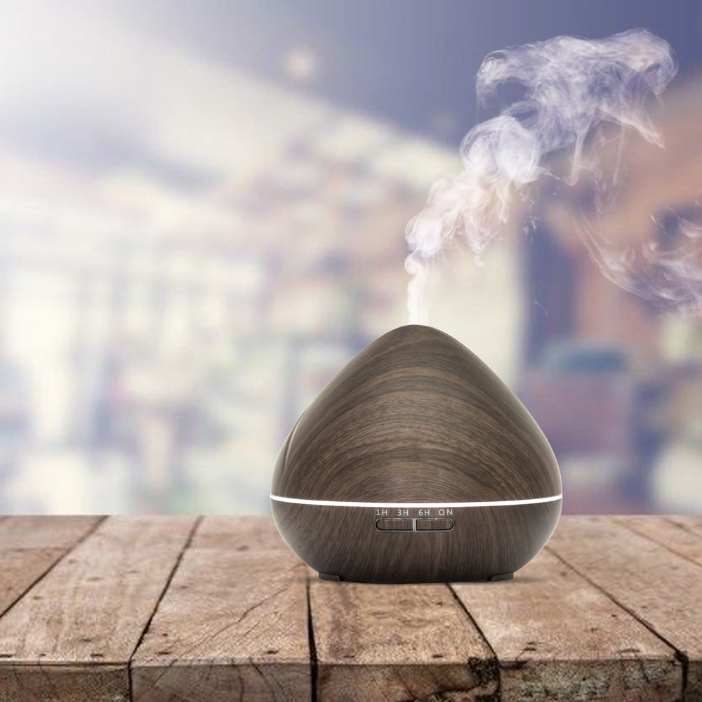Houten aroma diffuser in druppelvorm met LED-licht, afstandsbediening, timeropties (1u, 3u, 6u, continu) en instelbare lichtinstellingen.